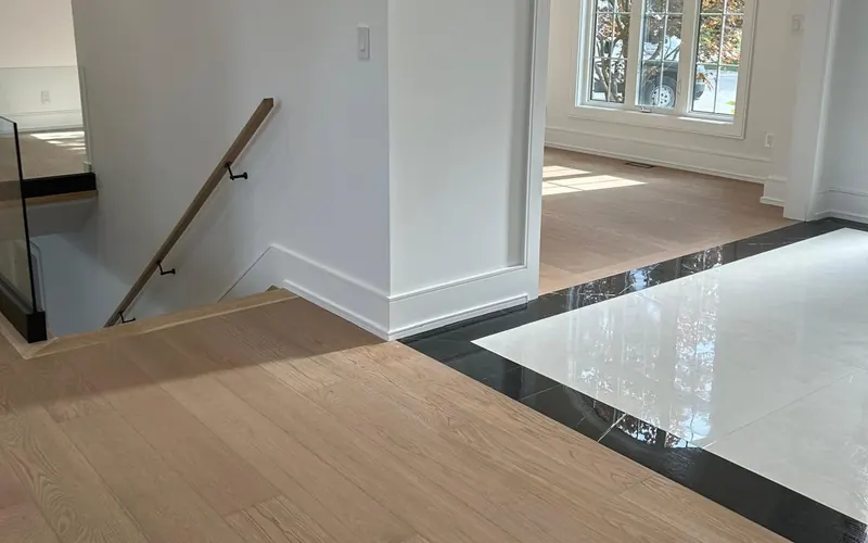 New white baseboards and oak flooring meeting a marble entry in a renovated Toronto home